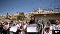 Displaced Syrians from the northern city of Afrin, hold placards during a demonstration to condemn violations by local Turkish-backed factions in front of the UN office in the northern Kurdish Syrian city of Qamishli on June 1, 2020.