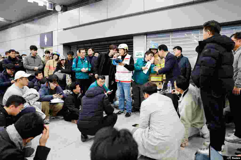 La gente escucha mientras un funcionario revela los nombres adicionales de los pasajeros que murieron en el accidente aéreo en el Aeropuerto Internacional de Muan, el 29 de diciembre de 2024.