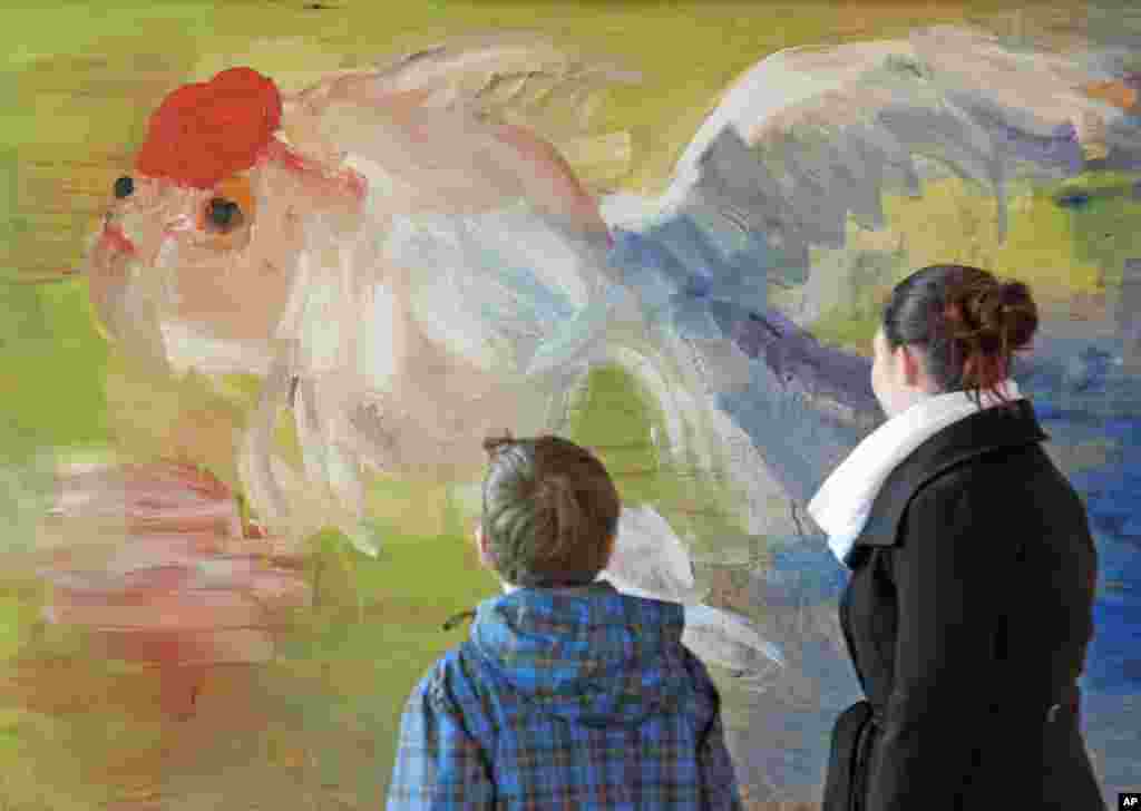 Mọi người đứng ở phía trước bức tranh sơn dầu "Goldfish" (1989) của Rainer Fetting trong buổi họp báo tại triển lãm 'Tuần triển lãm tranh,’ một dự án với Nhà triển lãm Raab của Berlin, ở Kulturfabrik tại thành phố Apolda, miền trung nước Đức. Triển lãm kéo dài tới ngày 14 tháng 7 năm 2015.