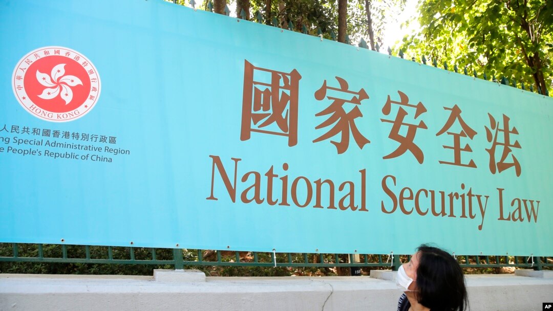 一名婦女走過香港街頭宣傳港版國安法的廣告牌。（2020年6月30日）
