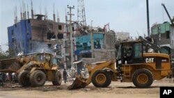 Para pekerja menggunakan bulldozer dan traktor untuk membersihkan reruntuhan gedung pabrik garmen di Savar, dekat Dhaka, Bangladesh (29/4).