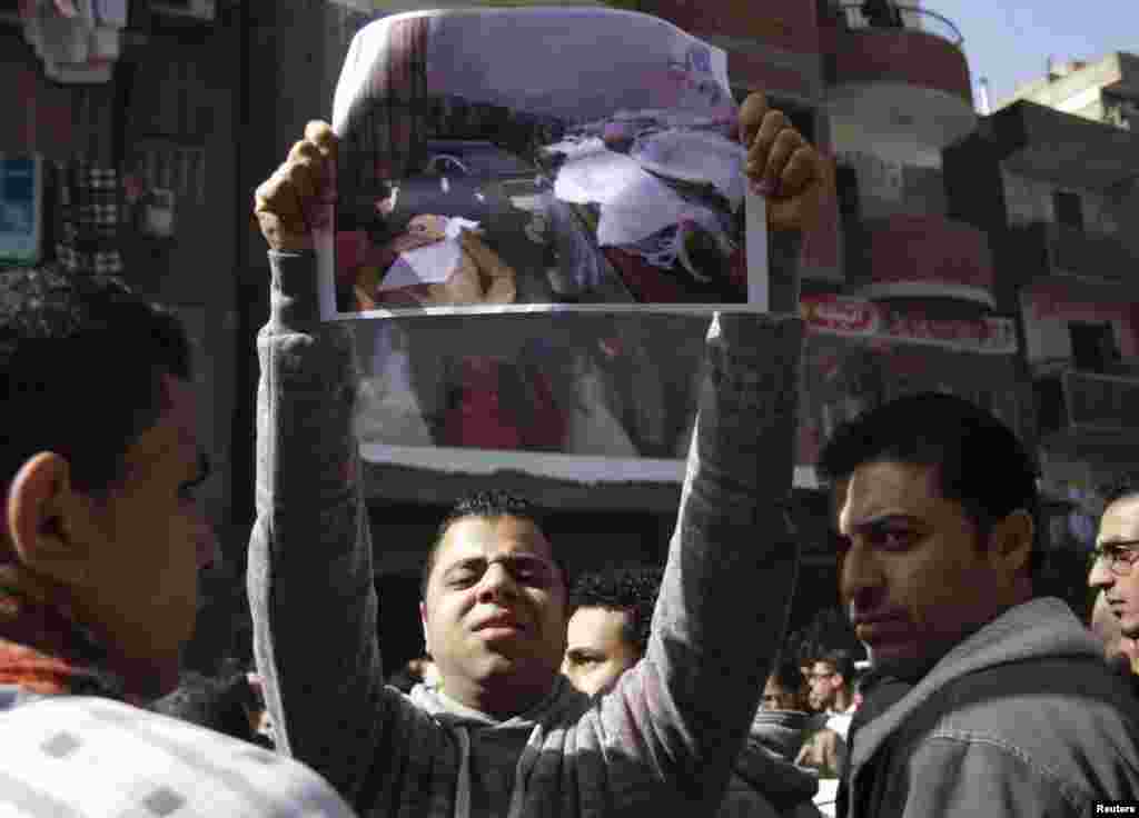 Friends of one of the soccer fans killed on Sunday carry his picture during his funeral, in Cairo, Feb. 9, 2015.