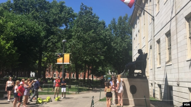 资料照片：游人与哈佛大学的约翰·哈佛铜像合影。