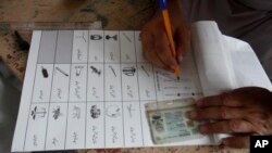 An election worker prepares ballot paper for a tribesman, waiting to cast his vote in a polling station during an election for provincial seats in Jamrud, a town of Khyber district, Pakistan, Saturday, July 20, 2019.