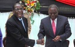FILE - Zimbabwean President Robert Mugabe, left, shakes hands with Prime Minister Morgan Tsvangirai, May 22, 2013, after he signed the new constitution into law in Harare.