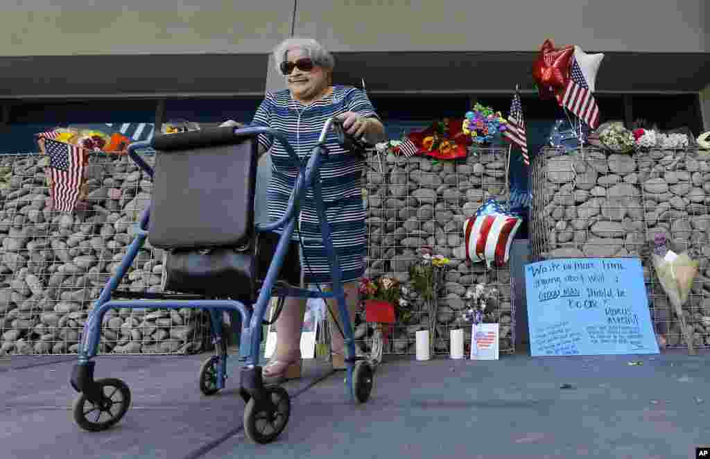 A woman walks from a makeshift memorial after paying her respects at the local offices of the late Arizona Republican Sen. John McCain, Aug. 26, 2018, in Phoenix. 