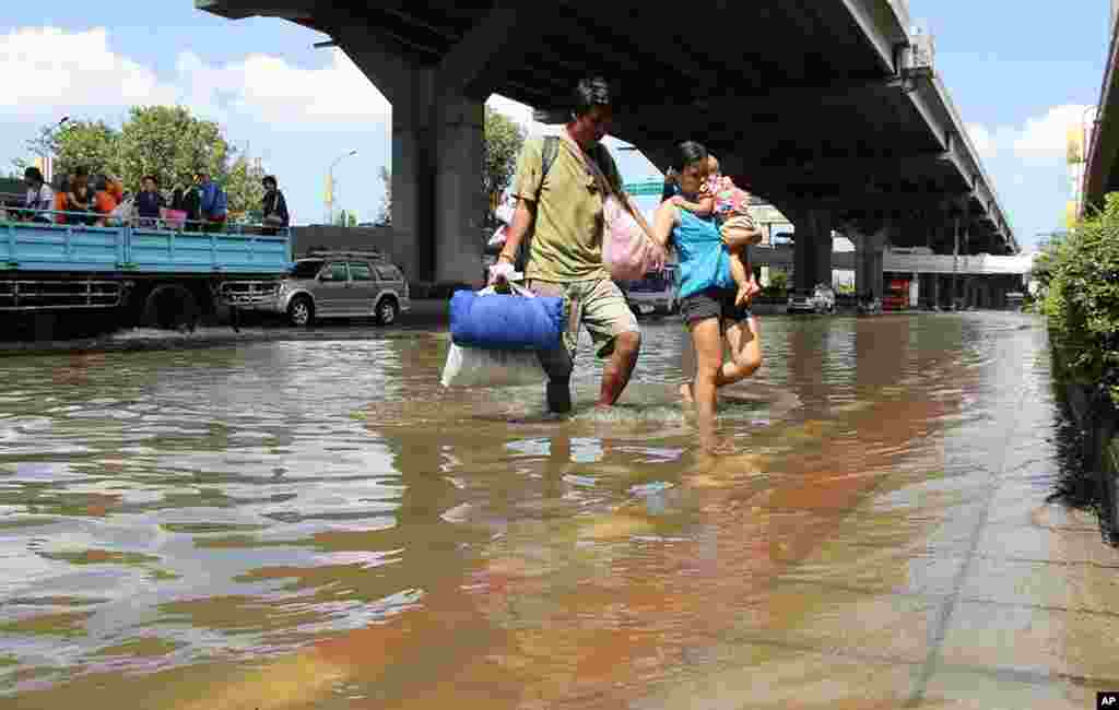 A family wades through the water rising in front of the Don Mueang evacuation center, October 25, 2011 (VOA - G. Paluch).