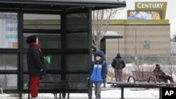 A woman and her grandson wait for a bus, near the fenced-in Century movie theater, the site of the deadly 2012 shootings, in Aurora, Colorado, January 15, 2013.