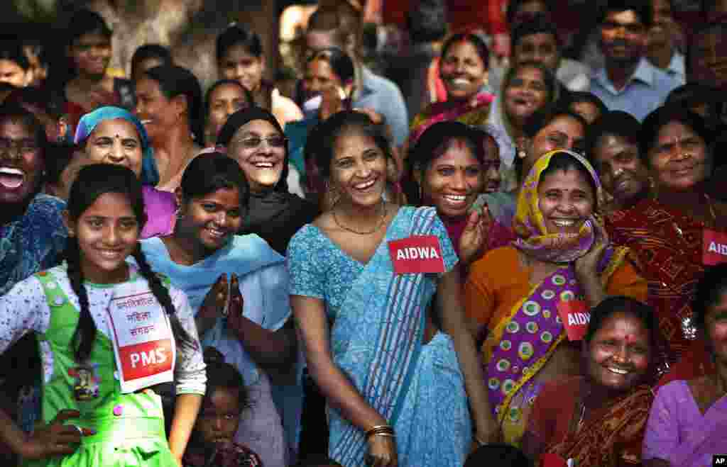 Perempuan di India tertawa melihat polisi terjatuh dalam sebuah pertunjukan mengenai kekerasan seksual dan cara-cara untuk melawannya, dalam peringatan Hari Perempuan Internasional di New Delhi (8/3). (AP/Saurabh Das)