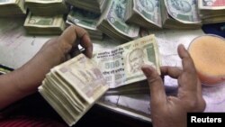 An employee counts Indian currency notes at a cash counter inside a bank in Kolkata, June 18, 2012. 