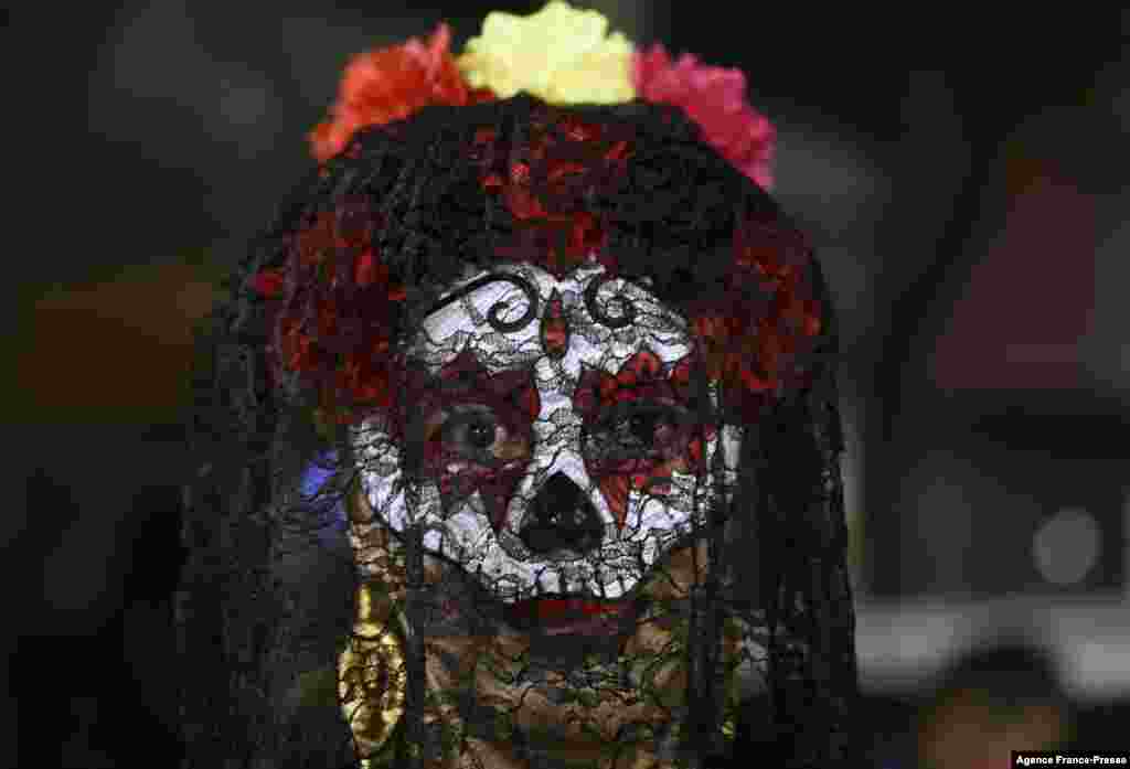 A transgender person looks on near offerings for victims of hate crimes on an alter, as part of Day of the Dead ceremonies, by civil organisations for the human rights of transgender people in Mexico City, Nov. 2, 2021.