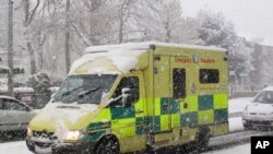 FILE - An Emergency Ambulance drives through a snow storm in Ealing, London.
