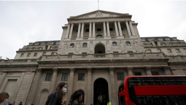 FILE - Pedestrians wearing face masks walk past the Bank of England in London, March 11, 2020.