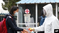 Seorang siswa perempuan yang memakai masker membersihkan tangannya dengan cairan pembersih sebelum memasuki area Sekolah Menengah Pertama Kumsong di Pyongyang, Korea Utara, pada 3 November 2021. (Foto: AP/Cha Song Ho)