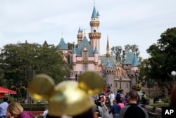 FILE - In this Jan. 22, 2015 file photo, visitors walk toward the Sleeping Beauty's Castle in the background at Disneyland Resort in Anaheim, Calif. (AP Photo/Jae C. Hong, File)