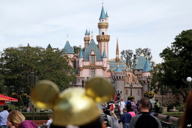 FILE - In this Jan. 22, 2015 file photo, visitors walk toward the Sleeping Beauty's Castle in the background at Disneyland Resort in Anaheim, Calif. (AP Photo/Jae C. Hong, File)