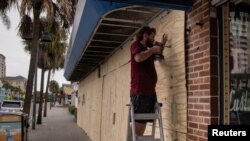 Un hombre protege las ventanas de su negocio en Clearwater Beach, Florida, ante la llegada del huracán Idalia. 