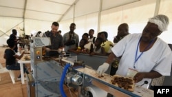 FILE - Visitors watch as employees of a Chocolatier in the Ivory Coast explain and show the different stages of processing cocoa into chocolate during the 5th edition of the ice cream and chocolate festival in Abidjan on May 19, 2018. 