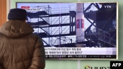 A man watches a news report on North Korea's planned rocket launch as the television screen shows file footage of North Korea's Unha-3 rocket which launched in 2012, at a railway station in Seoul, Feb. 3, 2016. 