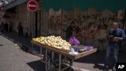 Palestinski prodavac sa tezgom ispred zatvorene prodavnice u Ramali na Zapadnoj obali. 2. maj, 2023. (Foto: AP/Nasser Nasser)