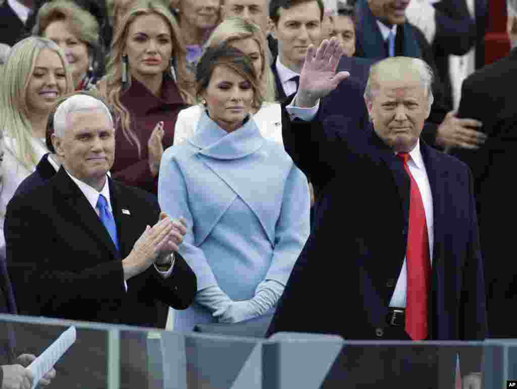 도널드 트럼프 미국 45대 대통령이 20일 워싱턴 DC 국회의사당에서 열린 취임식(오른쪽)에서 관중을 향해 손을 흔들고 있다. 왼쪽은 부인 멜라니아 여사.