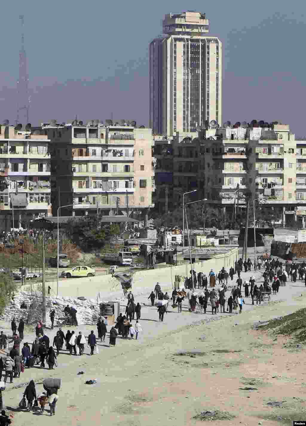 Civilians carry their belongings as they walk at the Karaj al-Hajez crossing in Aleppo, Feb. 9, 2014. 