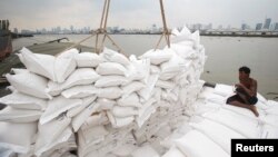 A migrant worker unloads sacks of rice from a barge to a cargo ship on The Chao Phraya River in Bangkok, Thailand, Aug. 27, 2014. 