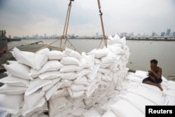 A migrant worker unloads sacks of rice from a barge to a cargo ship on The Chao Phraya River in Bangkok, Thailand, Aug. 27, 2014.