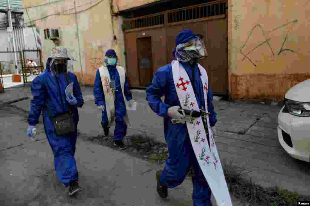 Filipino Catholic priests Eduardo &quot;Ponpon&quot; Vasquez Jr. and Rey Amancio, wearing personal protective equipment, make their way to a home to bless a deceased woman&#39;s ashes, amid the prohibition of religious gatherings, including funerals, during the lockdown to contain the coronavirus outbreak, in Caloocan, Metro Manila, Philippines.&nbsp;