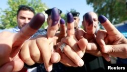 Iraqi security members show their ink-stained fingers after casting their vote at a polling station two days before polls open to the public in a parliamentary election, in Najaf, Iraq, May 10, 2018.