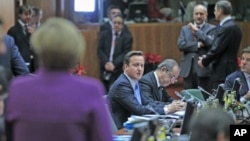 Britain's Prime Minister David Cameron (C) looks at Germany's Chancellor Angela Merkel (L) at a European Union summit in Brussels, December 9, 2011.