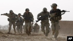 A US soldier returns fire as others run for cover during a firefight with insurgents in the Badula Qulp area, west of Lashkar Gah in Helmand province, southern Afghanistan, February 14, 2010