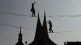 Tightrope artists balance on a rope in front of the Emmaus Monastery in Prague, Czech Republic.