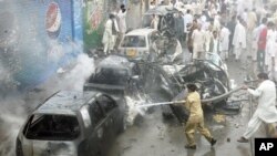 Firefighters spray water on damaged vehicles at the site of a car bomb blast in Quetta, Pakistan, Aug. 31, 2011