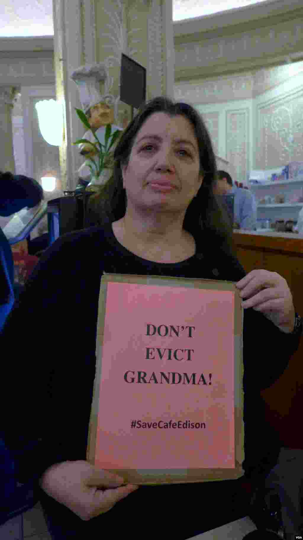 Barbara Nassberg shows off a poster protesting the move to close Café Edison, VOA / Jeff Lunden.