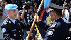 United Nations Police Pre-Deployment Training (UNPOL) officer Luis Carrilho (L) giving a flag to Longuinhos Monteiro (R) of the National Police of Timor-Leste (PNTL) during a ceremony in Dili, March 27, 2011