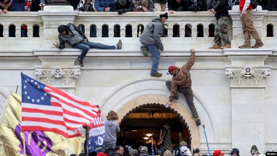 Una turba de simpatizantes del expresidente Donald Trump lucha contra policías en la puerta que rompieron al asaltar el Capitolio en Washington D.C. el 6 de enero pasado.