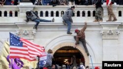 Una turba de simpatizantes del expresidente Donald Trump lucha contra policías en la puerta que rompieron al asaltar el Capitolio en Washington D.C. el 6 de enero pasado.