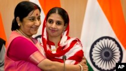 India's External Affairs Minister Sushma Swaraj, left, hugs Geeta, 23, a deaf and mute Indian woman who accidentally strayed into Pakistan as a child 12 years ago, during a press conference in New Delhi, India, Oct. 26, 2015. 