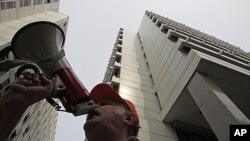 A public sector trade union member shouts slogans outside the Greek finance ministry, right, during a protest against the government's plans to suspend public servants on reduced pay, in Athens, September 20, 2011.