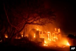 Flames consume a home on North Fairview Avenue as the Holiday fire burns in Goleta, Calif., July 7, 2018. The blaze has destroyed multiple homes.