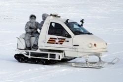 FILE - Russian military snowmobile moves on Kotelny Island, April 3, 2019. Missile launchers ply icy roads and air defense systems point menacingly into the sky at this Arctic military outpost.