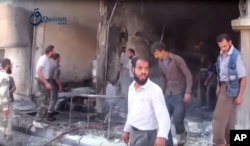 In this Oct. 1, 2015, image provided by the Syrian activist-based media group Qasioun News, Syrians use a fire extinguisher on the rubble of a building in the aftermath of a Russian airstrike, in Dair al-Asafeer, Syria.
