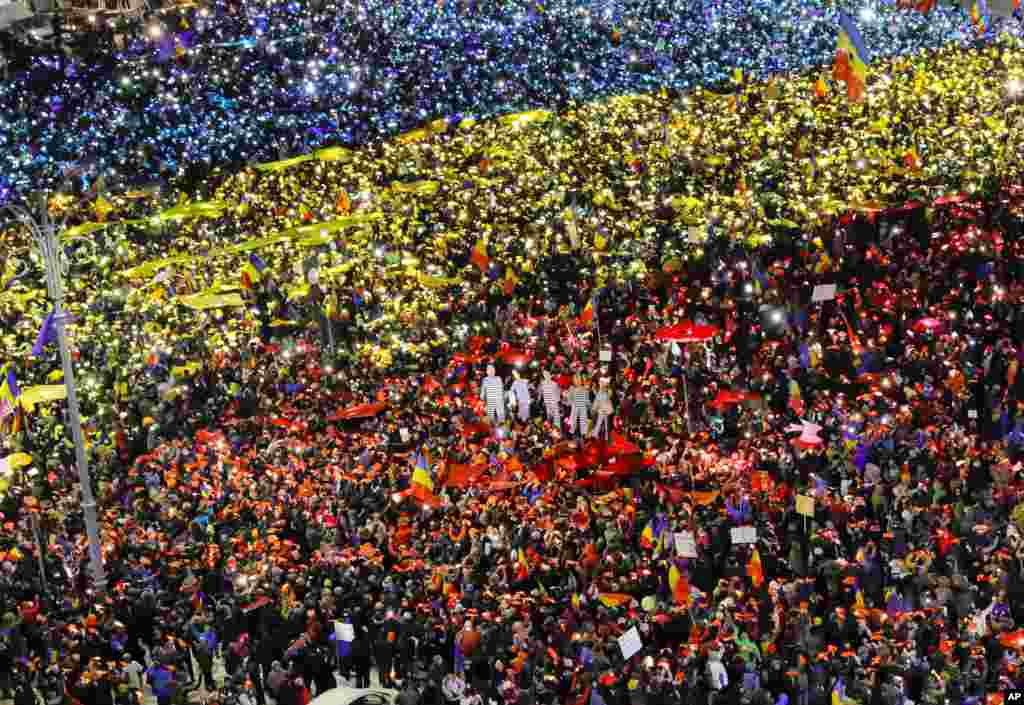 Para demonstran menyalakan lampu ponselnya untuk membentuk warna bendera Romania pada protes anti-pemerintah di Bukares.
