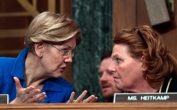 Sen. Elizabeth Warren, D-Mass., talks with Sen. Heidi Heitkamp, D-N.D., right, during a hearing on Capitol Hill in Washington, Jan. 30, 2018.