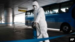 FILE - In this Feb. 1, 2020, file photo, State Commission of Quality Management staff in protective gear disinfects a ground transportation area at the Pyongyang Airport in Pyongyang, North Korea. Halting the spread of a new virus that has killed hundreds