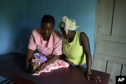 A maternal and child health aide, left, examines a newborn baby at a clinic in Pendembu, Kailahun district, Sierra Leone