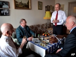 FILE - Russian President Vladimir Putin, second right, makes a toast to congratulate former head of the KGB intelligence group in Dresden, Germany, Lazar Matveyev, left, on his 90th birthday on the eve of Victory Day, in Zhulebino in Moscow, Russia, May 8, 2017. Matveyev, former KGB representative at the Ministry of State Security of the German Democratic Republic, was Putin's supervisor in Dresden in the second half of the 1980s.