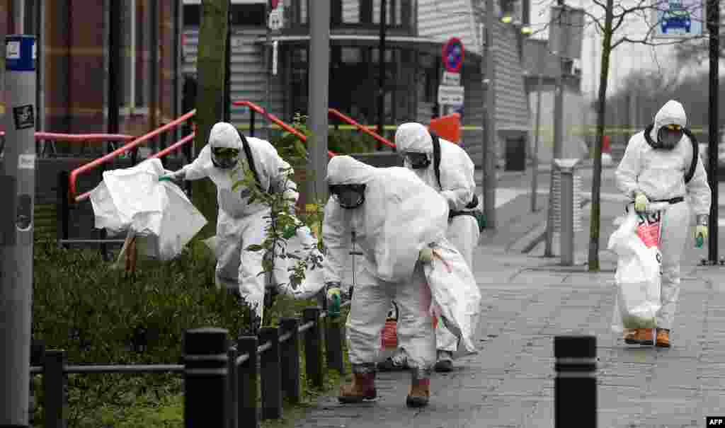 Những nhân viên dọn dẹp trong trang phục quần áo bảo hộ truy tìm những sợi amiăng (asbestos) quanh nhà ga xe lửa ở trung tâm thành phố Roermond, Hà Lan. Trung tâm thành phố Roermond bị phong tỏa và đặt trong tình trạng báo động sau một vụ cháy khiến amiăng tỏa ra khắp thành phố.