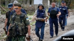 A sapper, center, carries a deactivated 120mm mortar shell after a defusing operation in the village of Semenovka, eastern Ukraine, July 13, 2014. 